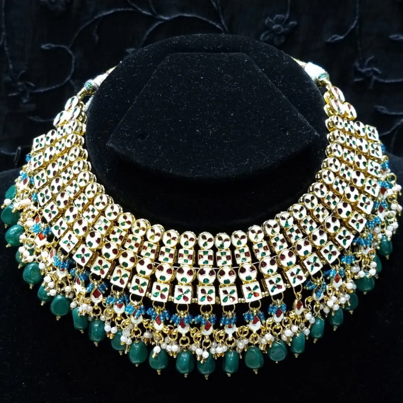 Bridal kundan piece is four layered set with dangling emeralds to match your festive.